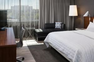 a hotel room with a bed and a chair at Le Méridien Chicago - Oakbrook Center in Oak Brook
