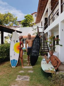 three men are standing next to their surfboards at No Worries Pipa in Pipa