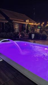 a swimming pool with purple lighting in front of a house at Noah Rosa Chalés in Praia do Rosa