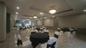 a banquet hall with black and white tables and chairs at Saltstayz Basil - Near Golf Course Road in Gurgaon