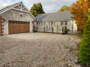 a house with a garage with a driveway at Westwood Cottage in Aboyne