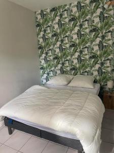 Bett in einem Schlafzimmer mit einer Wand mit Pflanzen in der Unterkunft Gite l'Atelier in Le Bû-sur-Rouvres