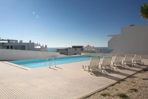 um grupo de cadeiras sentadas ao lado de uma piscina em Zahra Place - Stylish Flat na Nazaré