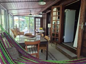 a hammock in a room with a table and chairs at Chalé de Madeira nr01 - Exuberante Flora e Fauna - IMBASSAI in Imbassai