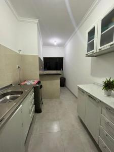 Una gran cocina blanca con fregadero y encimera. en Apartamento no centro de Dourados, en Dourados