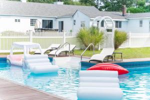 - une piscine avec des chaises blanches dans l'établissement Casa Hermes in Hamptons, à Westhampton Beach