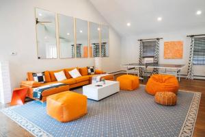 salon z pomarańczową kanapą i pomarańczowymi krzesłami w obiekcie Casa Hermes in Hamptons w mieście Westhampton Beach