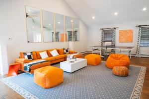 a living room with an orange couch and orange chairs at Casa Hermes in Hamptons in Westhampton Beach