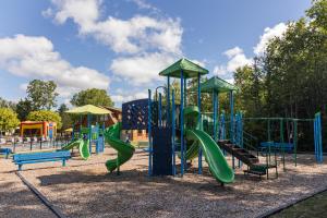 a playground with a green slide and benches at Jellystone Park TM Petoskey in Petoskey