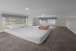 a white bedroom with a large white bed and two windows at Jellystone Park TM Petoskey in Petoskey +25 photos