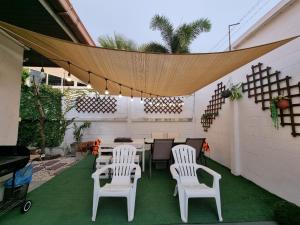 a patio with white chairs and a table and a fence at Peter Pan Poolvilla in Jomtien Beach
