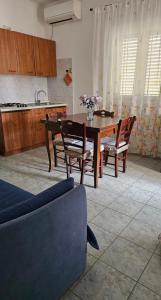 ein Wohnzimmer mit einem Tisch und Stühlen sowie eine Küche in der Unterkunft Azienda Agricola Gentile - la casa degli ulivi in Vieste