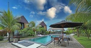 una piscina con tavolo e ombrellone di Seaside Hermitage Cosy Bungalow Near Canggu Beach a Canggu