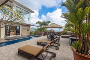 Elegant 6 Bedrooms Luxury Villa Near Pandawa Beach في نوسا دوا: منزل به مسبح وفناء به طاولات وكراسي