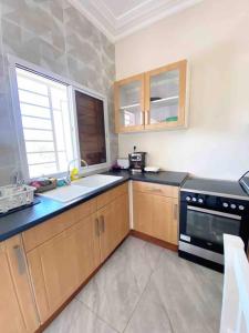a kitchen with wooden cabinets and a black appliance at KMR Apartment - Sira in Sere Kunda