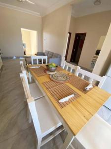 mesa de comedor con sillas blancas y mesa de madera en KMR Apartment - Sira, en Sere Kunda