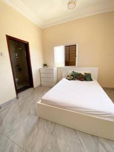 KMR Apartment - Sira في Sere Kunda: غرفة نوم مع سرير أبيض كبير في غرفة