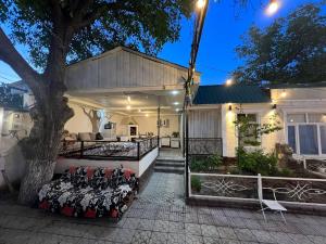 una casa con un portico con un letto e un albero di GREEN WEST House a Bishkek