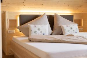 a bed with white sheets and pillows at Streuobst Chalets in Neukirch