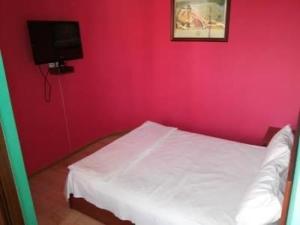 a pink bedroom with a white bed and a tv at Hrashq Hotel in Yerevan