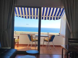 Sala de estar con mesa y vistas al océano en apartamentos Vv casafaromar, en Morro del Jable