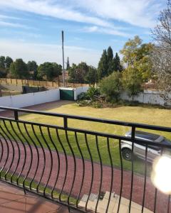 a fence on a balcony with a car in a yard at Sky view Guest House in Johannesburg