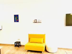 une chaise jaune dans une pièce avec un mur blanc dans l'établissement Résidence Deluxe, à Charleroi