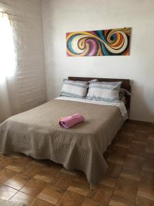 Una cama con una almohada rosa encima. en El Parralito hospedaje en Ciudad Lujan de Cuyo