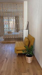 a living room with a yellow couch and a plant at TEODORA SUITE safran in Ravenna