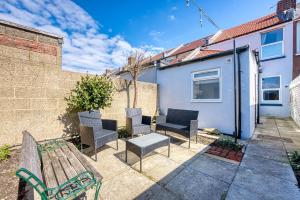 a patio with a bench and chairs and a building at Modern 2-Bed Stylish Contractor House, Prime Portsmouth Location & Parking - By Blue Puffin Stays in Portsmouth
