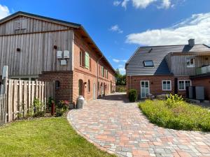 a brick building and a barn with a brick driveway at Ferienwohnung „lütte Stuuv“ - Hof Mühlenkoppel in Hasselberg