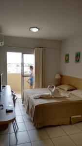 カルダス・ノバスにあるFlat - Condomínio Golden Dolphin Expressのベッド付き寝室に立つ女性