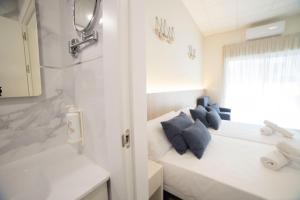 Baño blanco con almohadas azules y ventana en Hostal Altea Karma en Altea