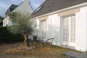 een tafel en stoelen naast een boom voor een huis bij Location Golfe du Morbihan in Arradon