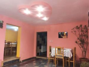 a dining room with a table and a pink wall at Pensiunea Trei brazi Scărișoara in Scărişoara
