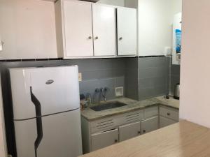 Una cocina con gabinetes blancos y un refrigerador blanco. en Departamento Zona Varese Piso 12, en Mar del Plata
