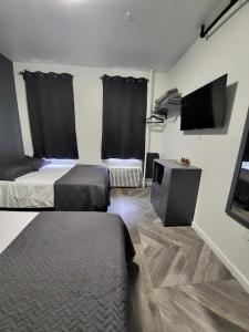 een kamer met 2 bedden en een televisie in een kamer bij Shefah Hotel in Union City