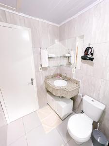 a white bathroom with a toilet and a sink at Pousada do Bosque Bento in Bento Gonçalves