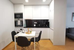 cocina con mesa blanca y sillas negras en OÁSIS apartments, en Viana do Castelo