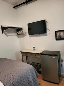 een slaapkamer met een bed en een bureau met een televisie aan de muur bij Shefah Hotel in Union City