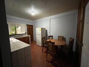 uma cozinha com uma mesa e um frigorífico branco em Rustical House Celeste em Bijagua