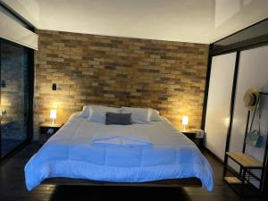 um quarto com uma cama grande e uma parede de tijolos em La ceiba cabaña em La Vega