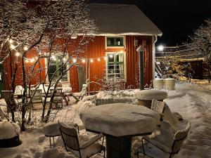 ein schneebedecktes Haus mit einem Tisch und Stühlen in der Unterkunft Lilla Hotellet in Tranemo