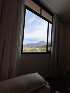 a bedroom with a window with a view of a mountain at Apartamento familiar no centro em Nova Friburgo in Nova Friburgo
