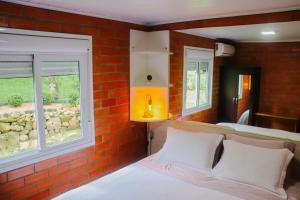 um quarto com uma parede de tijolos, uma cama e um candeeiro. em Pousada do Bosque Bento em Bento Gonçalves