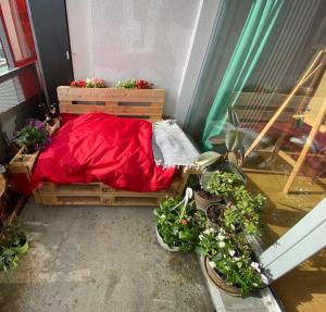 a small bed with red sheets and potted plants at Schöne Wohnung 5 Minuten von München Messe. in Munich