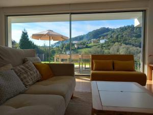 ein Wohnzimmer mit einem Sofa und einem großen Fenster in der Unterkunft Casa moderna julio y agosto in Ferrol