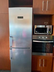 a stainless steel refrigerator in a kitchen next to a microwave at Hermoso y tranquilo departamento frente al mar. in Concón