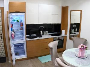 a kitchen with a table and an open refrigerator at Apartman Bajka in Zlatibor