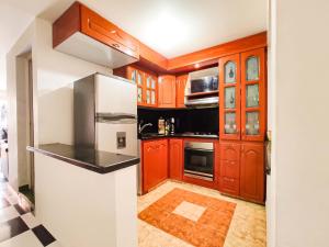 a kitchen with wooden cabinets and a white refrigerator at Precioso apartamento cerca del Aeropuerto de Bogta in Bogotá